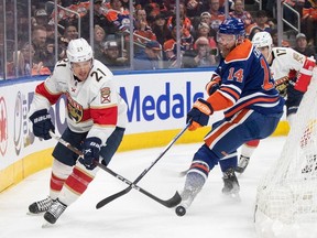 Florida Panthers' Nick Cousins (21) and Edmonton Oilers' Mattias Ekholm (14) battle for the puck during first period NHL action in Edmonton on Saturday December 16, 2023.