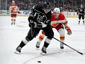 Los Angeles Kings center Anze Kopitar, left, controls the puck next to Calgary Flames center Blake Coleman during the second period of an NHL hockey game in Los Angeles, Saturday, Dec. 23, 2023.