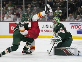 Minnesota Wild defenseman Jon Merrill, left, collides with Calgary Flames center Martin Pospisil during the second period of an NHL hockey game Thursday, Dec. 14, 2023, in St. Paul, Minn.