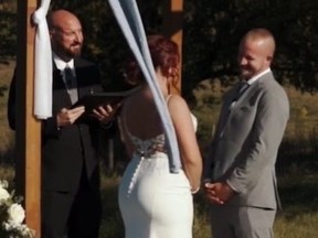 Screengrab of bride, groom and officiant at outdoor wedding where groom promises to "smack that a** every chance I get."