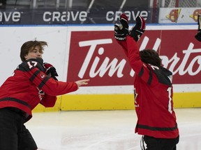Canada's Macklin Celebrini (17) tosses a glove at Fraser Minten (12) following the team photo at the IIHF World Junior Hockey Championship in Gothenburg, Sweden, Thursday, Dec. 28, 2023.