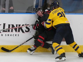 Sweden's Zeb Forsfjall (21) pushes Canada's Owen Beck (8) into the boards at the IIHF World Junior Hockey Championship in Gothenburg, Sweden on Friday, Dec. 29, 2023.