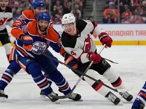 Edmonton Oilers defenceman Darnell Nurse (25) battles for the puck against New Jersey Devils forward Nathan Bastian (14) on Sunday, Dec. 10, 2023, in Edmonton.
