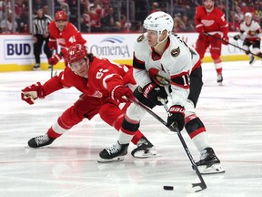 Tim Stutzle of the Ottawa Senators tries to get around the stick of Moritz Seider of the Detroit Red Wings at Little Caesars Arena on December 9, 2023 in Detroit.