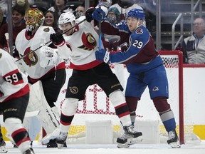 Ottawa Senators defenseman Travis Hamonic jostles for position in front of the net with Colorado Avalanche center Nathan MacKinnon, right, during the second period of an NHL hockey game Thursday, Dec. 21, 2023, in Denver.