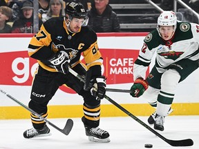 Sidney Crosby of the Pittsburgh Penguins skates with the puck against Brock Faber of the Minnesota Wild at PPG PAINTS Arena on December 18, 2023 in Pittsburgh.