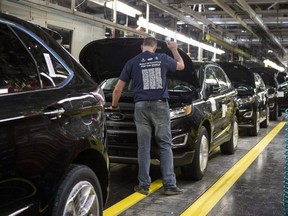 A worker examines a Ford Edge on a production line at the Ford Assembly Plant in Oakville, Ont., on Feb. 26, 2015.