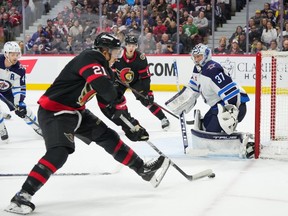 Senators winger Mathieu Joseph trieds to control the puck in front of Jets netminder Connor Hellebuyck in the second period of Saturday's game.