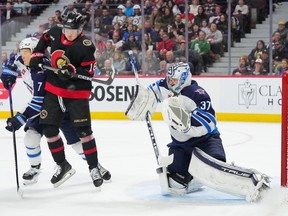 OTTAWA, CANADA - JANUARY 20: Tim St?tzle #18 of the Ottawa Senators attempts to deflect the puck past Connor Hellebuyck #37 of the Winnipeg Jets during the second period at Canadian Tire Centre on January 20, 2024 in Ottawa, Ontario, Canada.