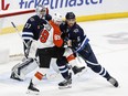 Winnipeg Jets' Brenden Dillon (5) defends against Philadelphia Flyers' Cam Atkinson (89) in from of goaltender Connor Hellebuyck (37) during second period in Winnipeg on Saturday.