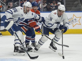 Derek Ryan (10) of the Edmonton Oilers is held up by Mark Giordano (55) and Max Domi (11) of the Toronto Maple Leafs at Rogers Place in Edmonton on Jan. 16, 2024.