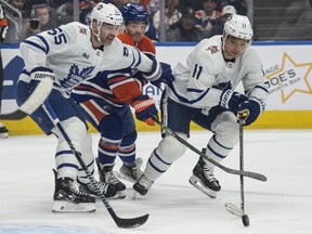 Derek Ryan, centre, of the Edmonton Oilers is held up by Mark Giordano, left, and Max Domi of the Toronto Maple Leafs at Rogers Place in Edmonton on Tuesday, Jan.16, 2024.