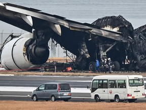 Officials look at the burnt wreckage of a Japan Airlines (JAL) plane on the tarmac at Tokyo International Airport at Haneda in Tokyo on January 3, 2024.