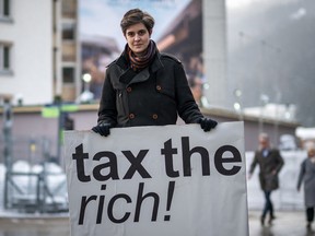 Austrian Marlene Engelhorn, who inherited from her family which owns the German chemical giant BASF, poses with a placard reading "Tax the rich!" at the annual meeting of the World Economic Forum (WEF) in Davos, on January 15, 2024.