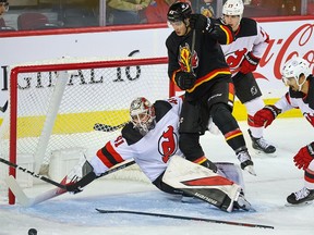 Calgary Flames forward Adam Ruzicka scrambles to reach a loose puck in front of New Jersey Devils goaltender Vitek Vanecek during NHL action in Calgary on Saturday, December 9, 2023.