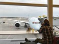 A traveller looks at an Air Canada plane as he waits for his flight at Pierre Elliott Trudeau International Airport in Montreal, Friday, Dec. 23, 2023.