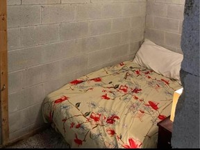 Twin bed in unfinished basement that resembles a jail cell for rent in Scarborough for $500 a month.