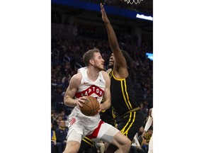 Toronto Raptors center Jakob Poeltl, left, drives to the basket against Golden State Warriors forward Kevon Looney, right, during the third quarter of an NBA basketball game, Sunday, Jan. 7, 2024, in San Francisco.