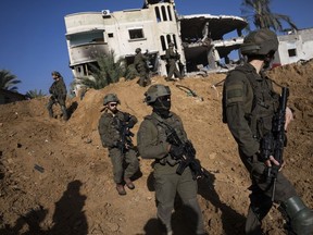 Israeli army troops are seen next to a destroyed building during a ground operation in Khan Younis, Gaza Strip, on Wednesday, Jan. 10, 2024.