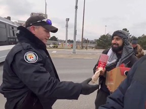 Toronto Police officers hand-deliver Tim Hortons coffee from one pro-Palestinian protester to others who managed to take up positions on the Avenue Rd. overpass at Hwy. 401 before cops shut it down again on Saturday, Jan. 6, 2023.