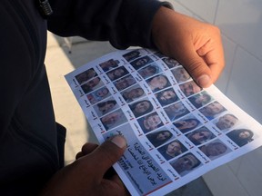 This photograph taken on January 20, 2024 in Rafah in the southern Gaza Strip shows a man holding a leaflet showing portraits of Israeli hostages held in Gaza.