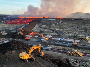 Aerial view taken on January 14, 2024 shows emergency personnel using diggers to build a protective wall after a volcanic eruption.