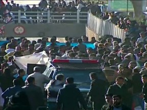 An image grab from a video released by state-run Iran Press news agency on January 3, 2024 shows a police vehicle surrounded by the crowd near the site where two explosions in quick succession struck a crowd.