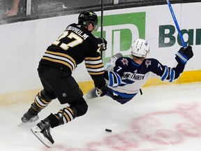 Boston Bruins' Hampus Lindholm (27) and Winnipeg Jets' Vladislav Namestnikov (7) battle for the puck during the first period of an NHL hockey game, Monday, Jan. 22, 2024, in Boston.