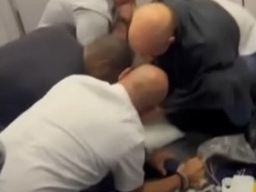 Screenshot of men restraining passenger on American Airlines flight.