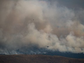 Helicopters fly past the Tremont Creek wildfire as it burns on the mountains above Ashcroft, B.C., on Friday, July 16, 2021.
