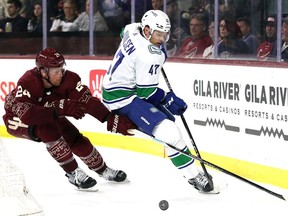 Noah Juulsen of the Vancouver Canucks skates with the puck against Brett Ritchie of the Arizona Coyotes during the third period at Mullett Arena on March 16, 2023 in Tempe, Arizona.