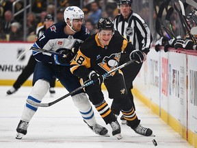 Adam Lowry (17) of the Winnipeg Jets checks Jesse Puljujarvi (18) of the Pittsburgh Penguins in the third period at PPG PAINTS Arena on Feb. 6, 2024, in Pittsburgh.
