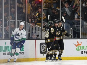 Boston Bruins celebrate a goal against the Vancouver Canucks during the second period while Elias Pettersson skates by at TD Garden on February 8, 2024 in Boston, Massachusetts.