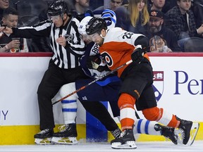 Jets’ Morgan Barron (centre) collides with Flyers’ Sean Walker (right) and linesman Steve Barton during the first period in Philadelphia Thursday.