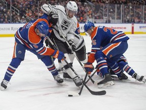 Cody Ceci (5) and Darnell Nurse (25) of the Edmonton Oilers battle for possession against Pierre-Luc Dubois (80) of the Los Angeles Kings at Rogers Place in Edmonton on Feb. 26, 2024.