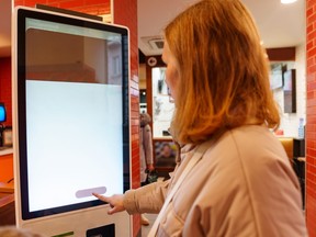 A woman makes a fast-food order via the self-service terminal.