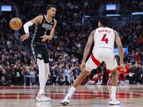 Victor Wembanyama of the San Antonio Spurs makes a pass as he's defended by Scottie Barnes of the Toronto Raptors at Scotiabank Arena on February 12, 2024 in Toronto.
