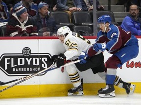 Boston Bruins centre Matthew Poitras, left, drives along the boards past Colorado Avalanche defenceman Caleb Jones, right, in the second period of an NHL hockey game Monday, Jan. 8, 2024, in Denver.