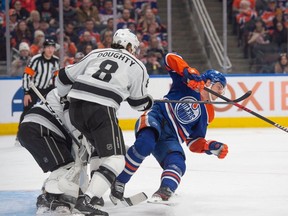 Mattias Janmark (13) of the Edmonton Oilers, is knocked down by Drew Doughty(8) of the Los Angeles Kings at Rogers Place in Edmonton on Feb. 26, 2024.