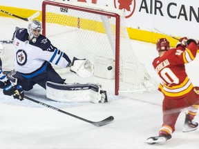 Calgary Flames center Jonathan Huberdeau fires the puck past Winnipeg Jets goaltender Connor Hellebuyck, bringing the Flames up 4-3, in the second period at the Saddledome on Monday, February 19, 2024.