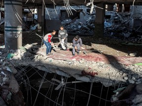 Children search debris near the exposed ceiling of a basement in a mosque that was destroyed during Israeli bombardment in Rafah in the southern Gaza Strip on February 14, 2024.