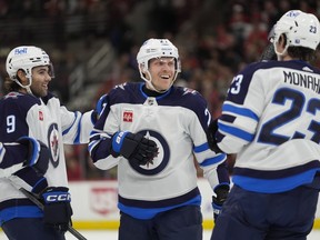 Winnipeg Jets left wing Alex Iafallo, left wing Nikolaj Ehlers and center Sean Monahan, from left, celebrate Ehlers' goal against the Chicago Blackhawks during the first period of an NHL hockey game Friday, Feb. 23, 2024, in Chicago.