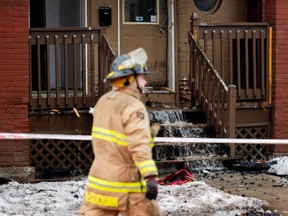 An Ottawa Fire Services firefighter walks in front of a damaged building on Osgoode Street in Sandy Hill in this Feb. 1 file photo.