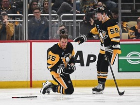 Noel Acciari of the Pittsburgh Penguins is checked on by Jake Guentzel after a hit by Brenden Dillon #5 of the Winnipeg Jets (not pictured) in the second period during the game at PPG PAINTS Arena on February 6, 2024 in Pittsburgh, Pennsylvania.