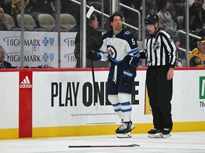 Brenden Dillon of the Winnipeg Jets is led to the penalty box by linesman Ben O'Quinn #91 after receiving a penalty for boarding in the second period during the game against the Pittsburgh Penguins at PPG PAINTS Arena on February 6, 2024 in Pittsburgh, Pennsylvania.
