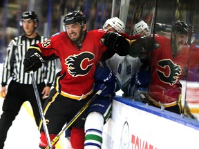Vancouver Canucks' Ben Hutton is crushed by Calgary Flames' Emile Poirier during a game in 2015.