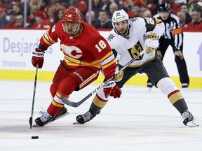 A.J. Greer #18 of the Calgary Flames and Michael Amadio #22 of the Vegas Golden Knights battle for the puck during the third period at the Scotiabank Saddledome on November 27, 2023 in Calgary, Alberta, Canada.