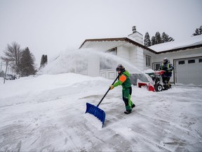 People use snowblowers and shovels on their walkways and driveways during a Winter Storm Warning in Saskatoon, Sask., Sunday, March 3, 2024.