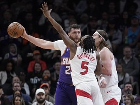 Phoenix Suns centre Jusuf Nurkic (20) keeps the ball away from Toronto Raptors guard Immanuel Quickley (5) and Toronto Raptors forward Kelly Olynyk (41) during the first half of an NBA basketball game in Phoenix, Thursday, March. 7, 2024.