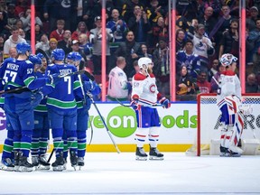 Canadiens defeceman David Savard and goalie Sam Montembeault lurk in the background as Canucks players celebrate a third-period goal Thursday night in Vancouver.